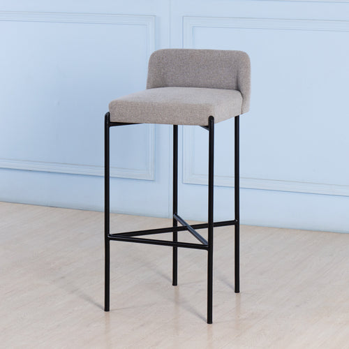 Bar stool with gray cushioned seat and black metal frame against a light blue wall.